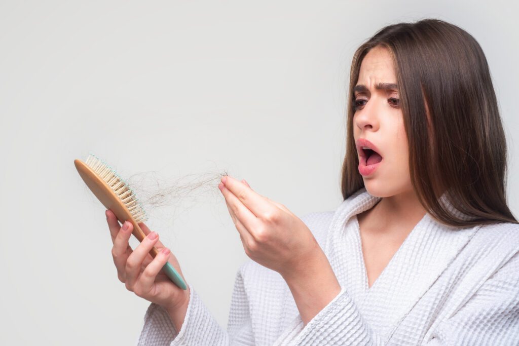 Woman shocked by hair fall while brushing, seeking treatment at the Best Hair Clinic in JP Nagar.
